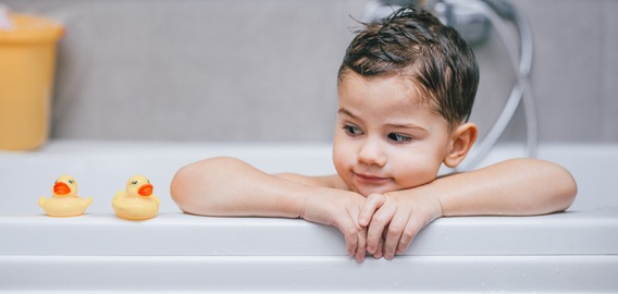 Bébé dans son bain avec des canards en plastique